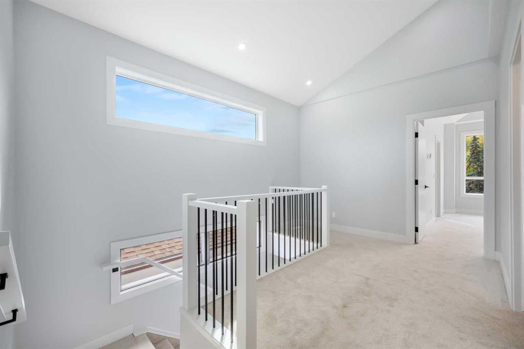 Upstairs landing with beige carpet, black metal railing, and a long horizontal window.