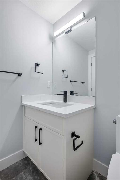 Bathroom vanity with a large mirror, black fixtures, and dark tile flooring.