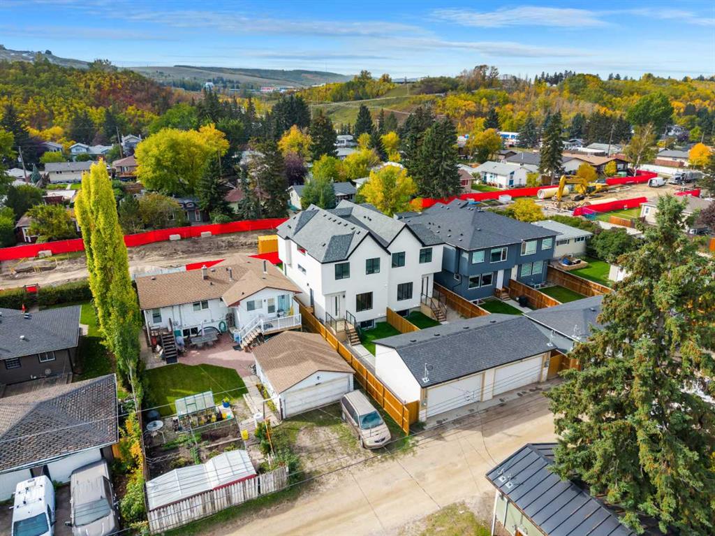 Aerial view of new white and blue homes with fenced yards and autumn trees.