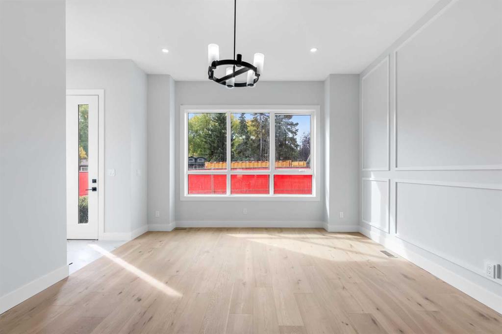 Vacant room with pale wood floors, decorative wall molding, and a large three-panel window.