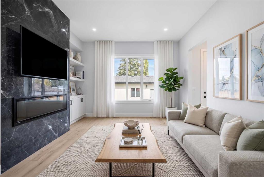 Staged living room with a gray sectional, wood coffee table, and dark marble fireplace wall.