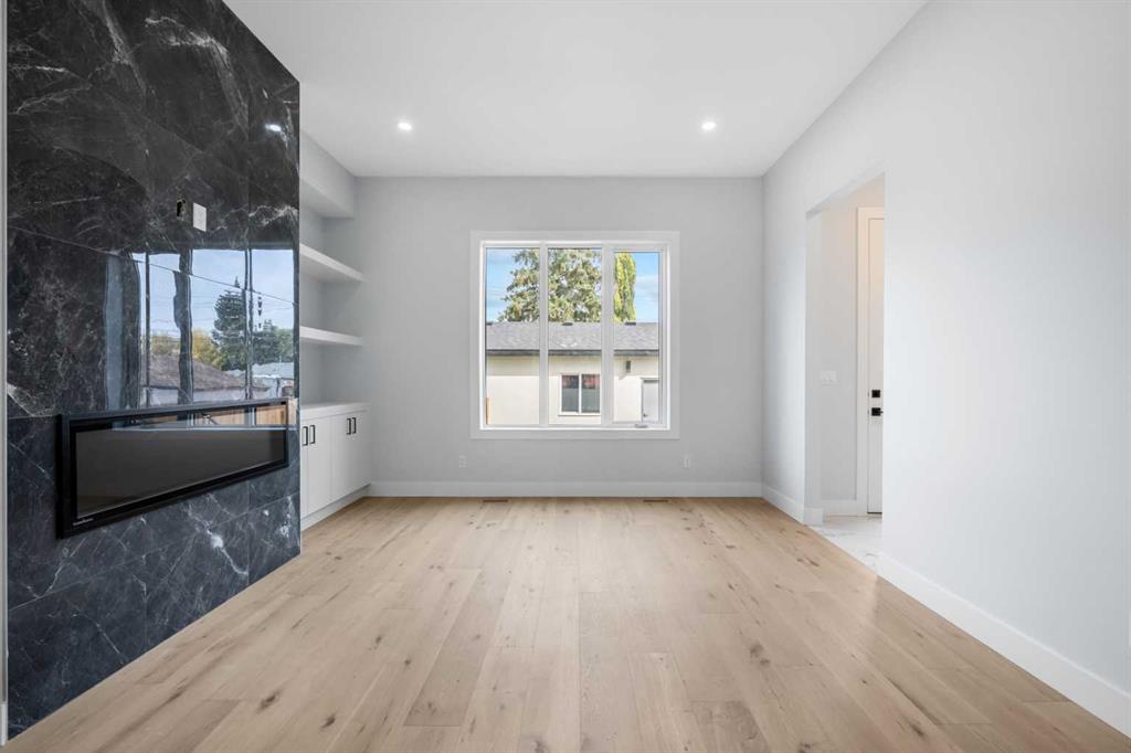 Unfurnished living room with a dark marble fireplace wall and pale wood floors.