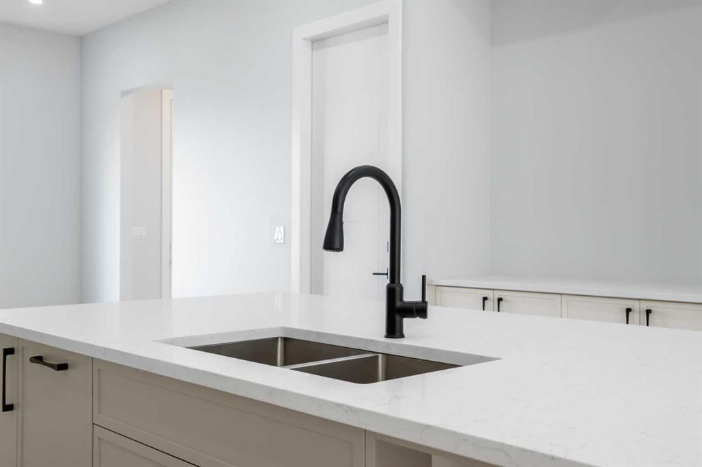 Kitchen island with a white quartz countertop, double sink, and matte black faucet.