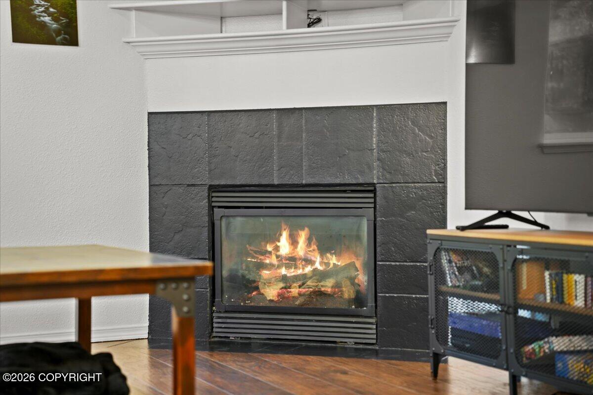 Living room fireplace with a dark stone surround, white mantel, and fire burning.