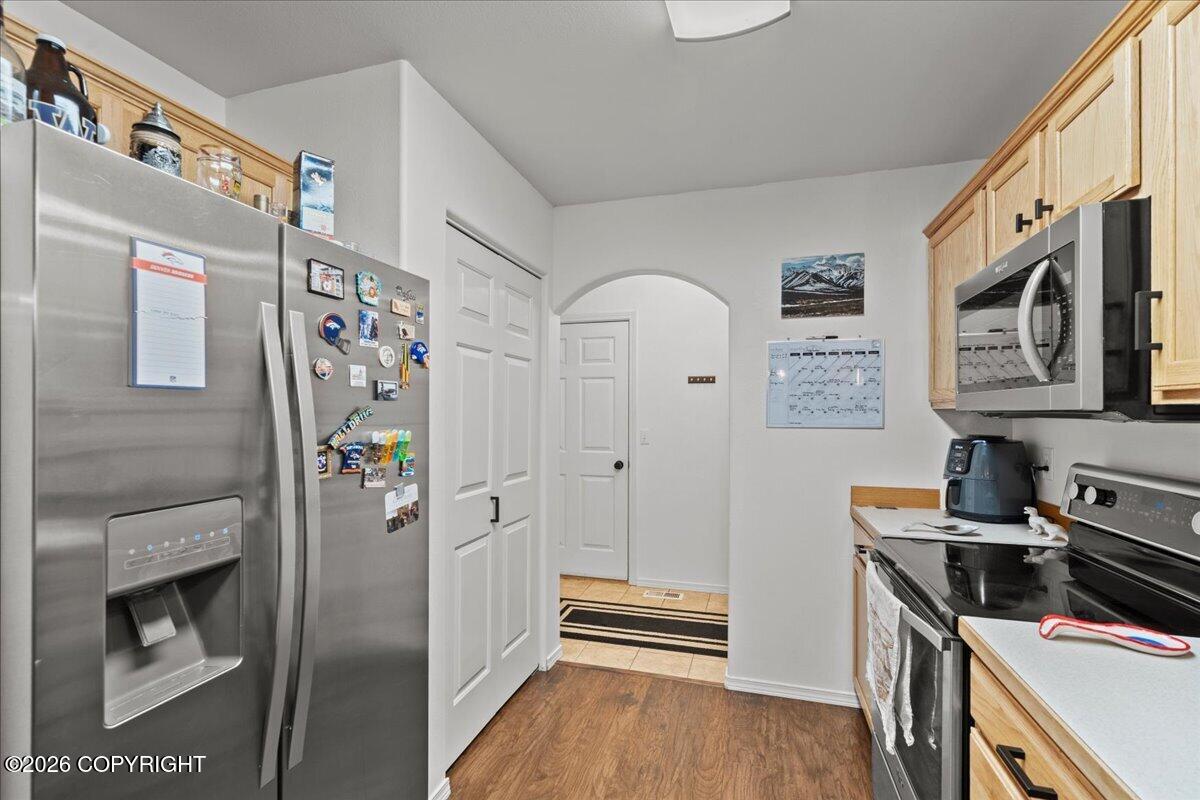 Kitchen with stainless steel appliances, light wood cabinets, and a doorway to the hall.