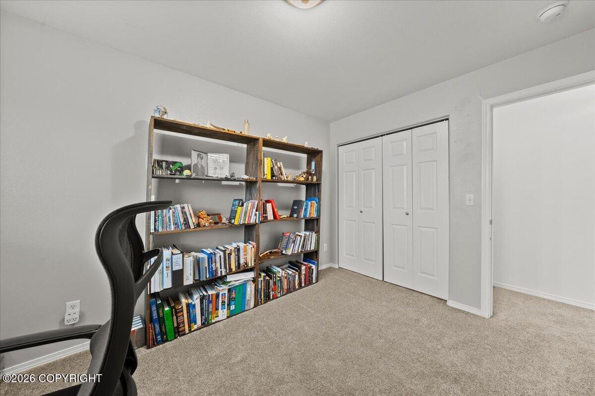 Office with wall-length bookshelves, a black desk chair, and white closet doors.