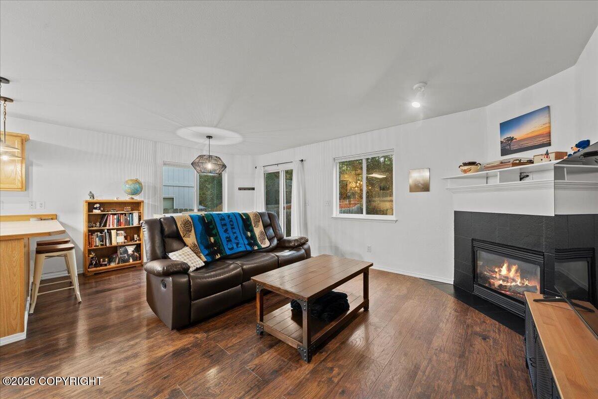 Living room with a leather sofa, hardwood floors, and a corner fireplace.