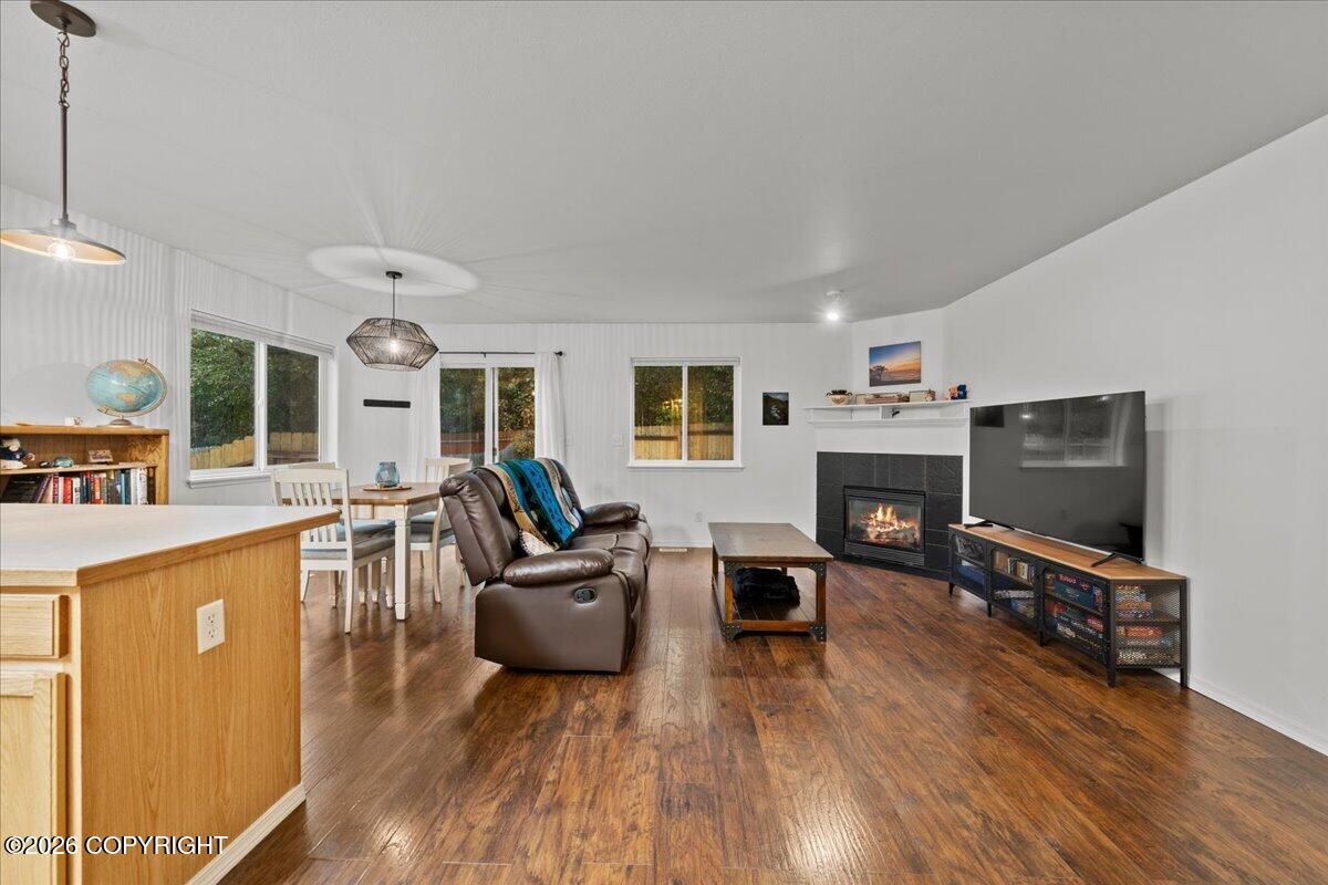 Open-plan living room with hardwood floors, leather recliner, fireplace, and large TV.