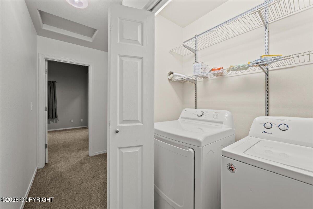 Laundry room with a white washer and dryer beneath wire storage shelves.