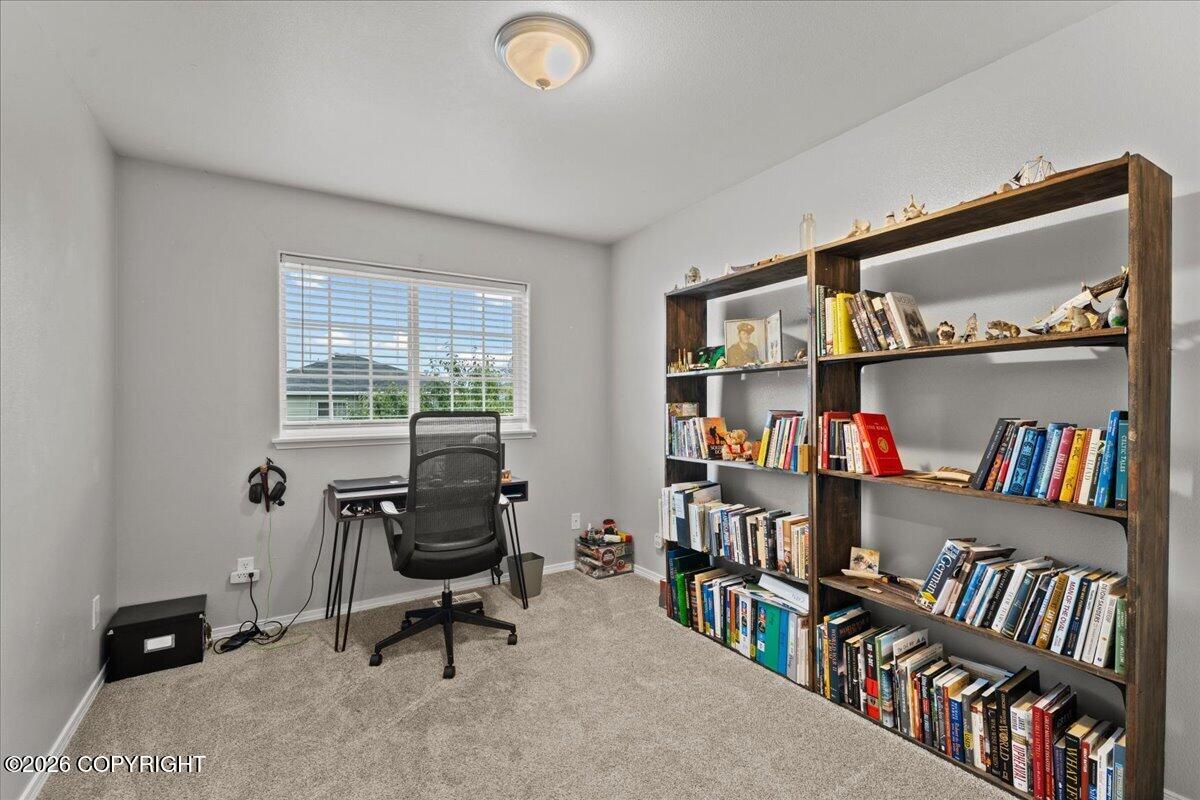 Home office with a desk beneath a window and two book-filled shelves.