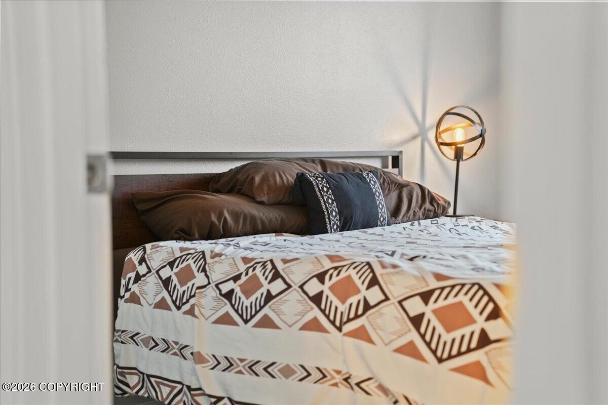 Bedroom with geometric-patterned bedding and a glowing globe floor lamp, seen through a doorway.