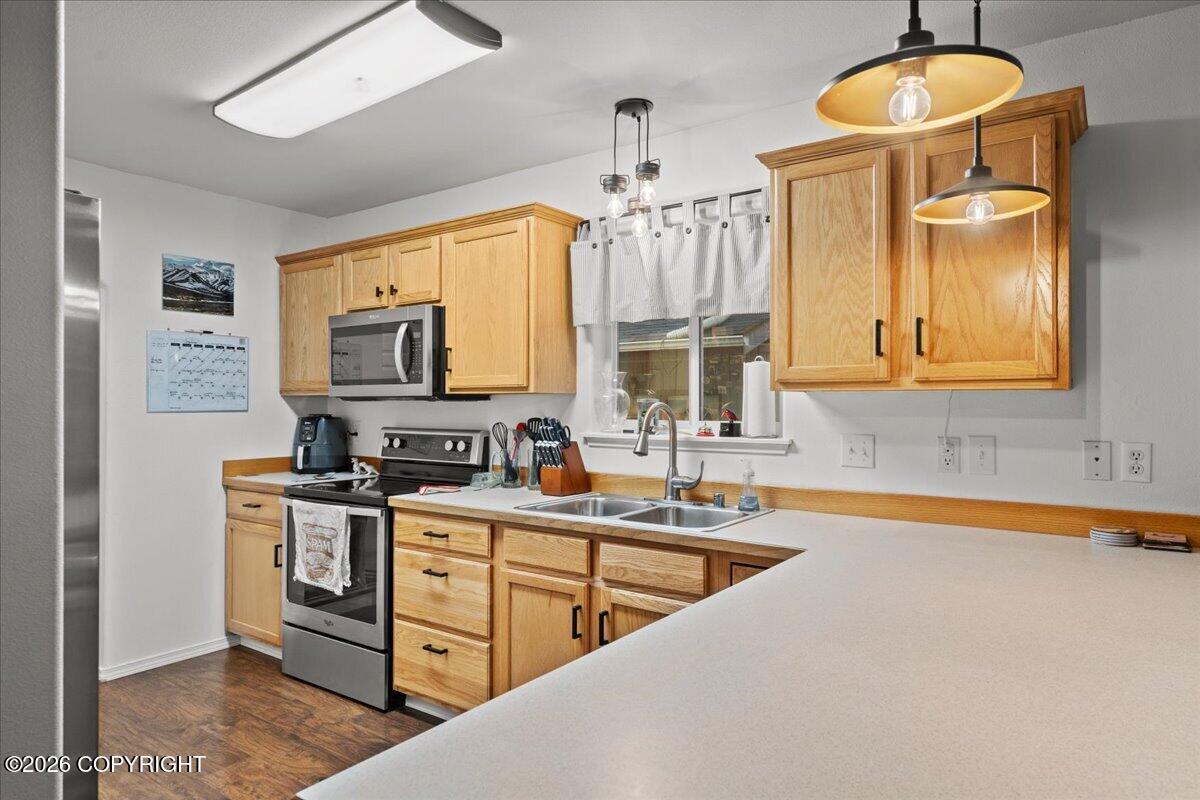 Kitchen with honey-colored wood cabinets, stainless steel appliances, and a large peninsula counter.