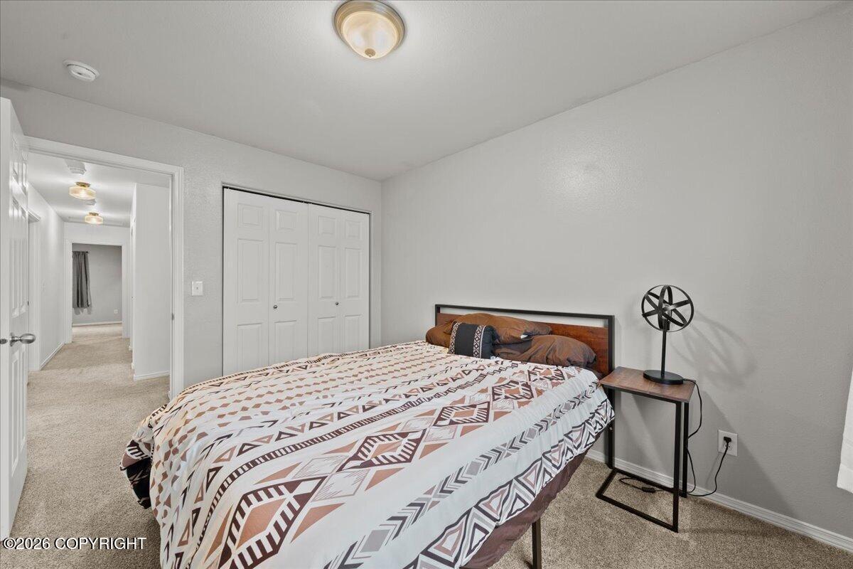 Bedroom with geometric patterned bedding, a white closet, and beige carpet.