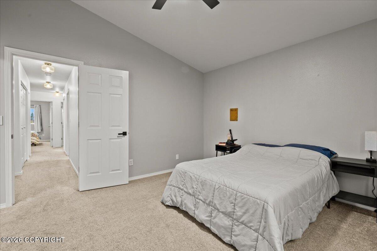 Bedroom with a white quilted bed, gray walls, and an open door to the hallway.