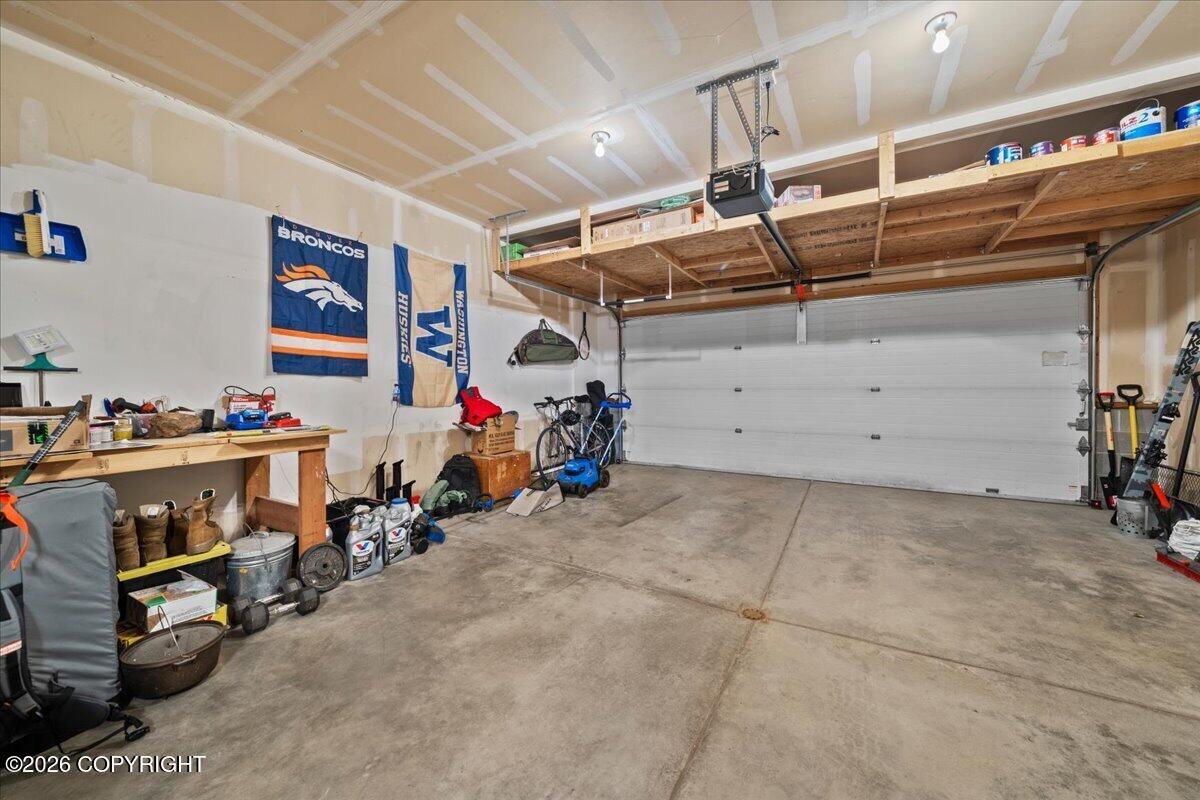 Garage with overhead storage, a workbench, bicycles, and sports banners.