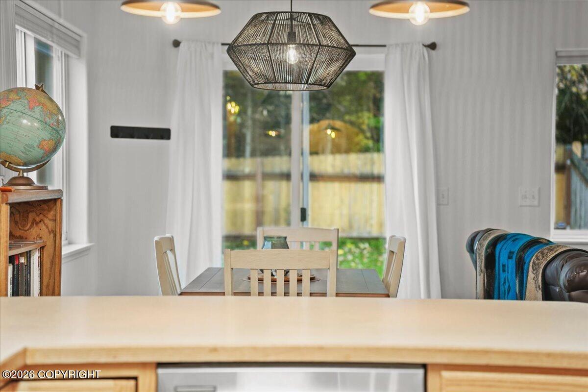 Dining area with a woven pendant light, wooden table, and sliding glass doors.