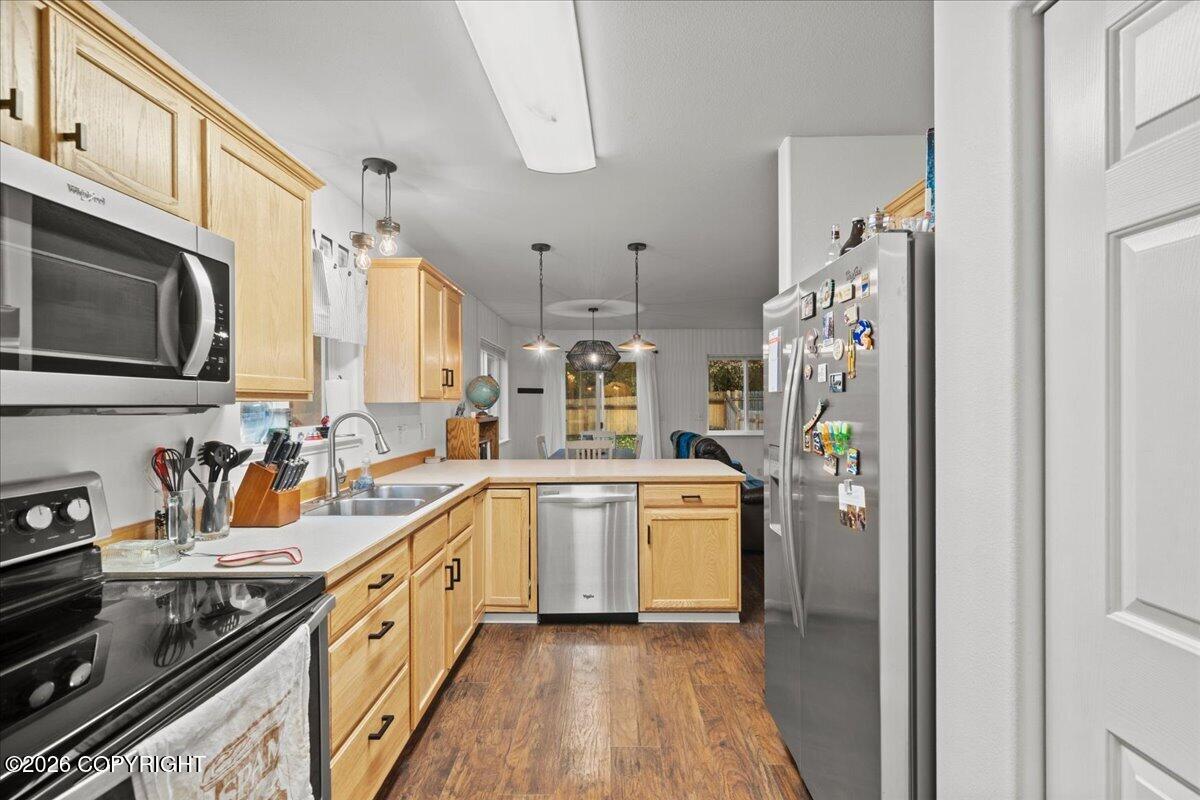 Kitchen with light wood cabinets, stainless steel appliances, and a peninsula counter.