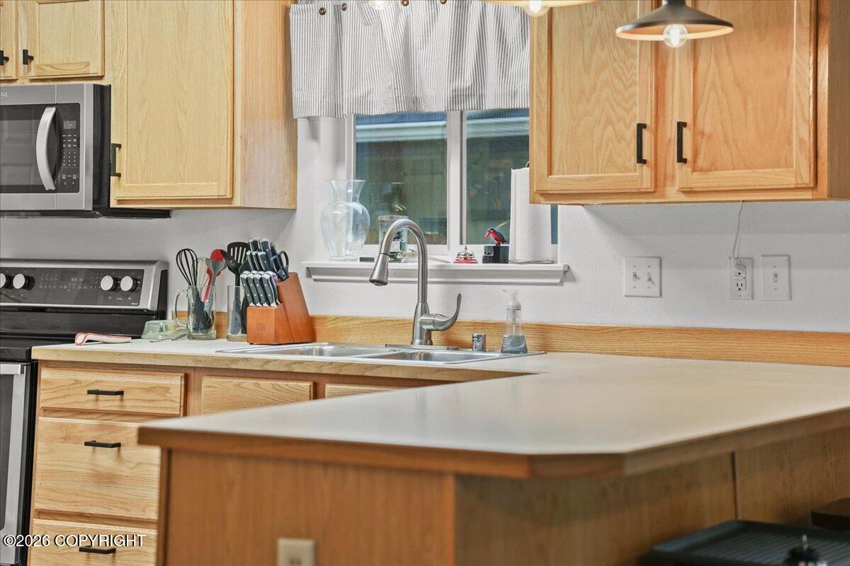 Kitchen with light wood cabinets, a large island, and a sink beneath the window.