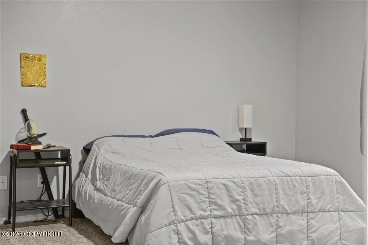 Bedroom with a white quilted bed, blue pillows, and dark bedside tables.