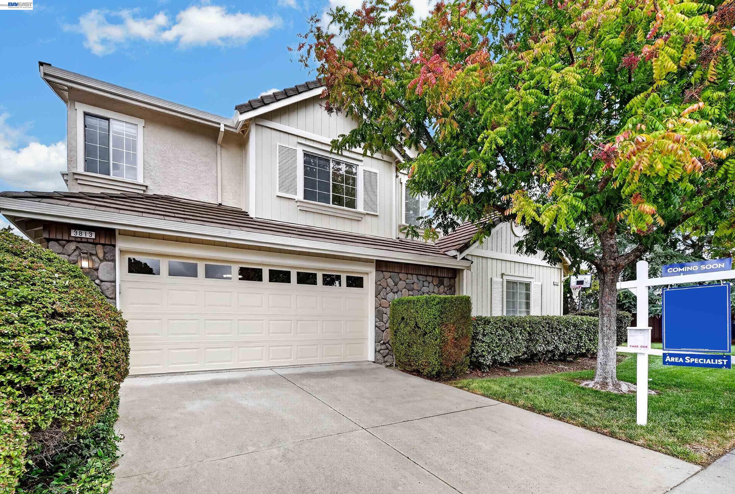 Two-story home with stone accents, a double garage, and a Coming Soon real estate sign.