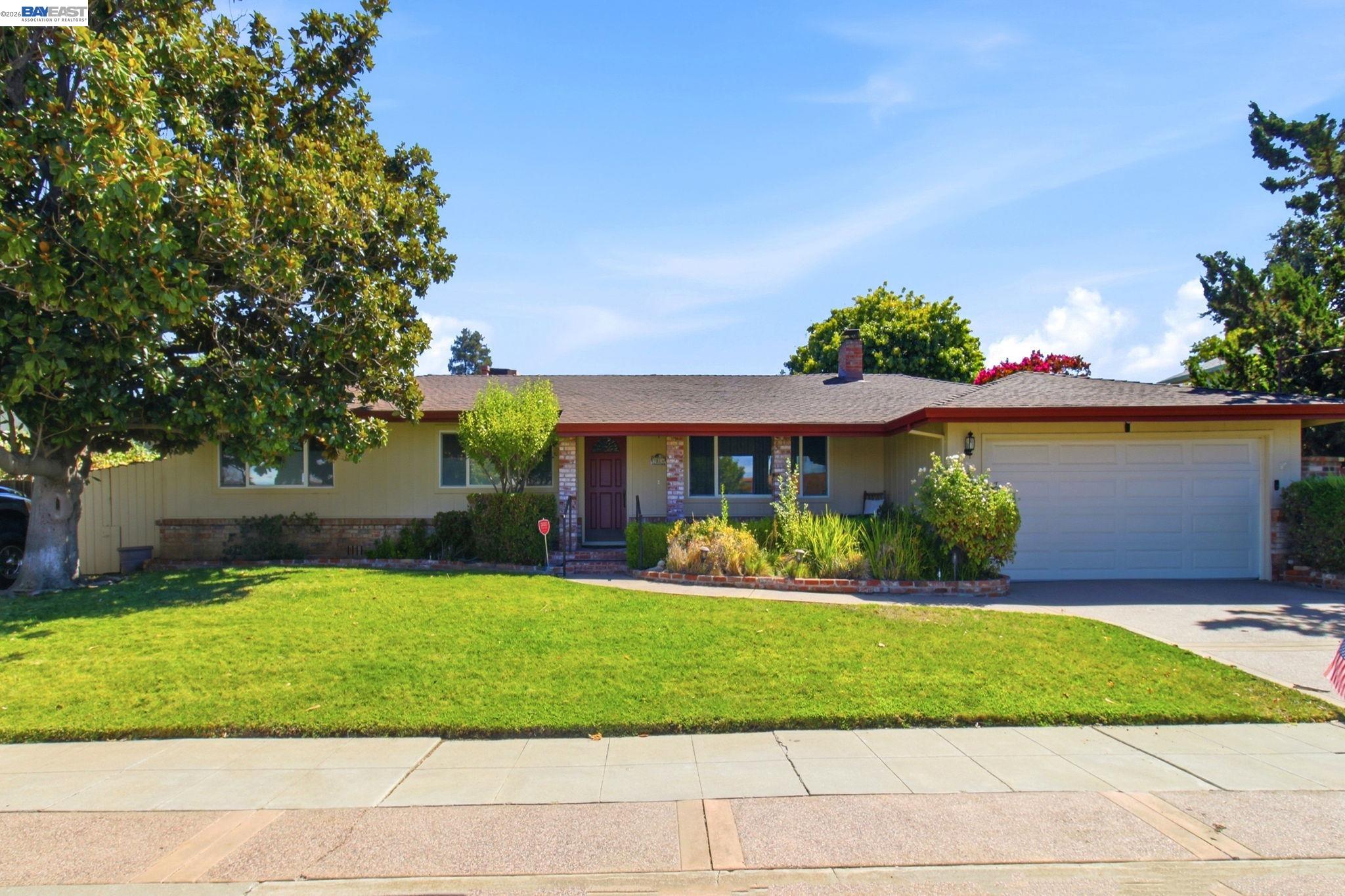 Single-story ranch home with a red front door, attached garage, and landscaped lawn.
