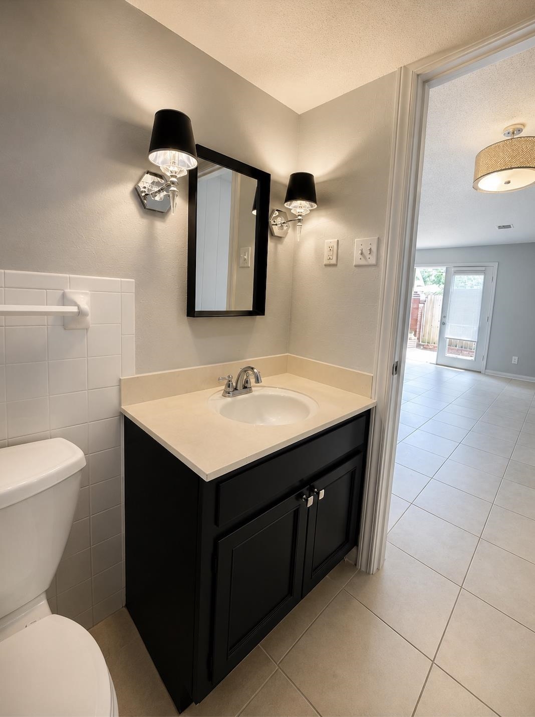 Bathroom with a black vanity, light countertop, framed mirror, and paired wall sconces.