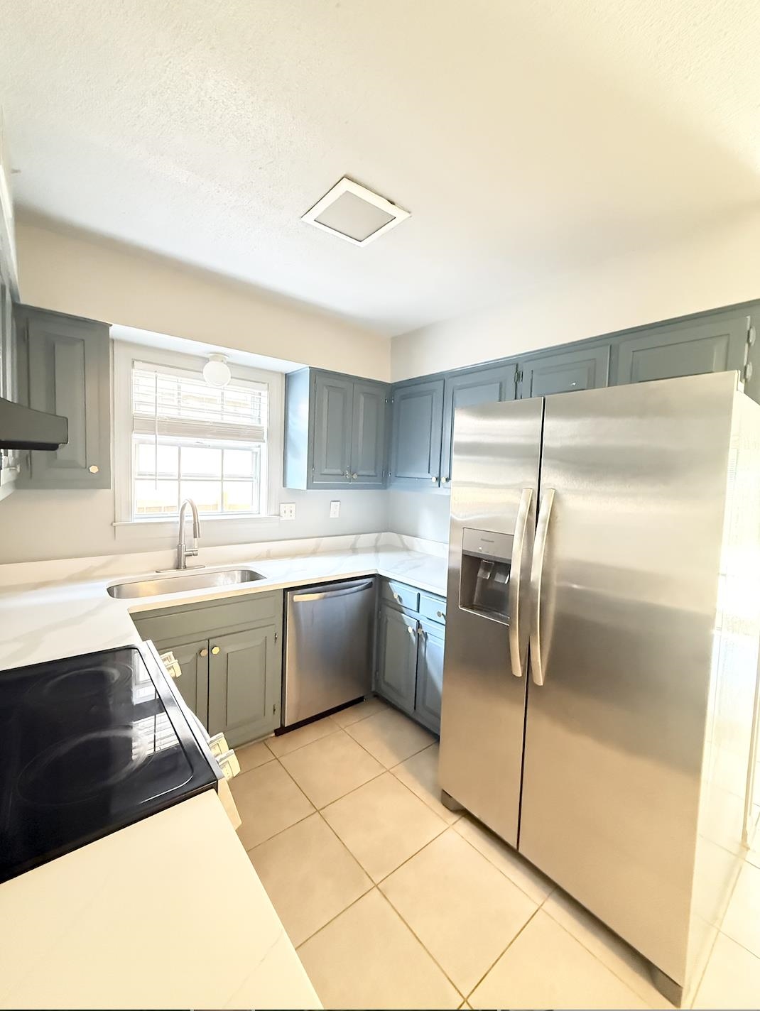 Kitchen with blue-gray cabinets, white counters, and stainless steel appliances.