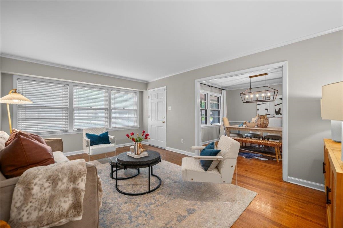 Living room with wide windows, hardwood floors, and an adjoining dining area.