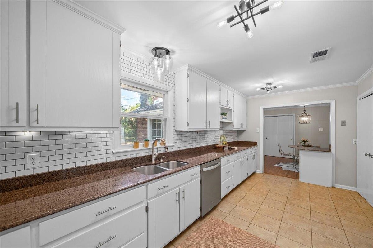 Updated kitchen with white cabinets, dark granite counters, subway tile backsplash, and a window above the sink.