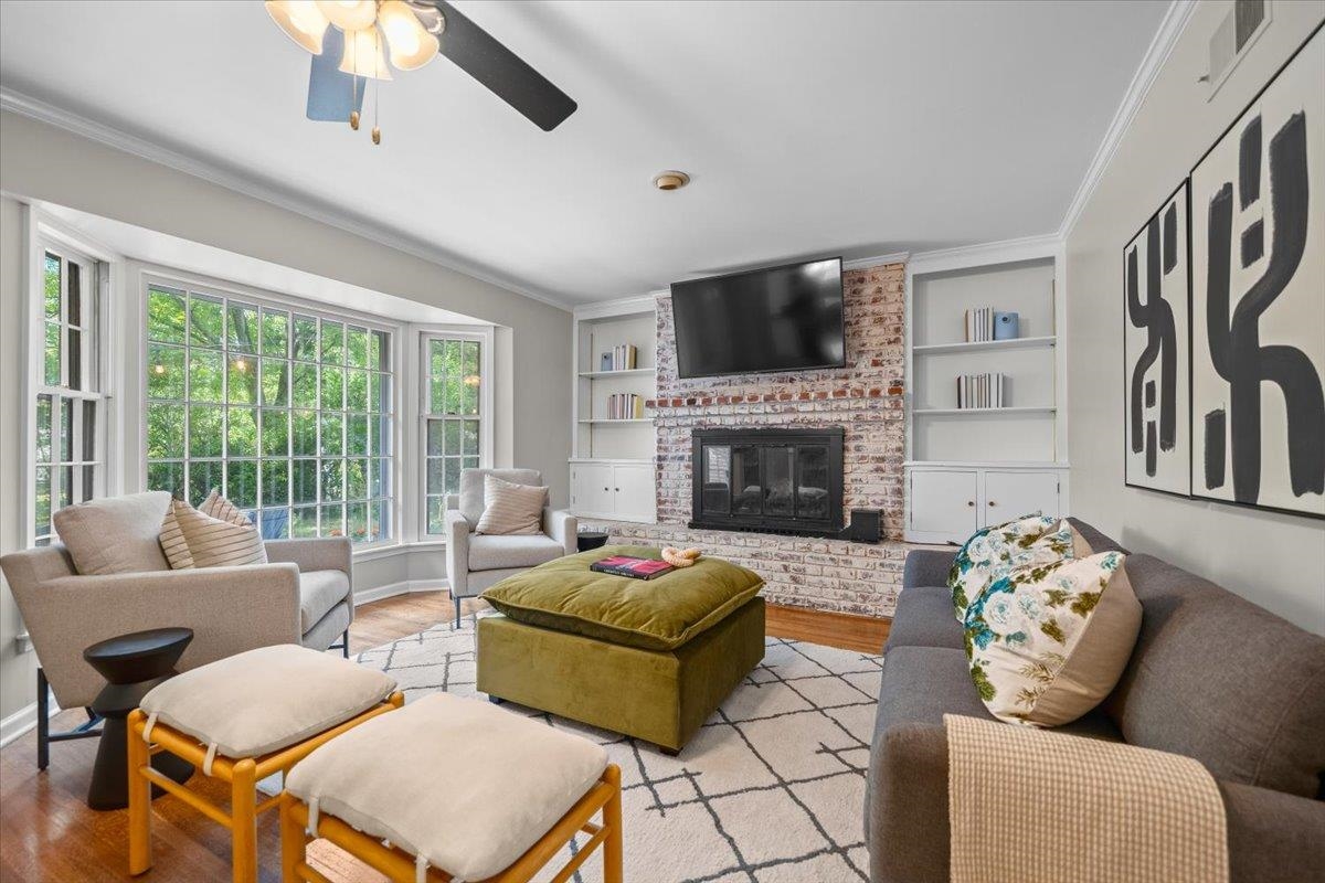 Living room with a brick fireplace, built-in shelves, and a large bay window.