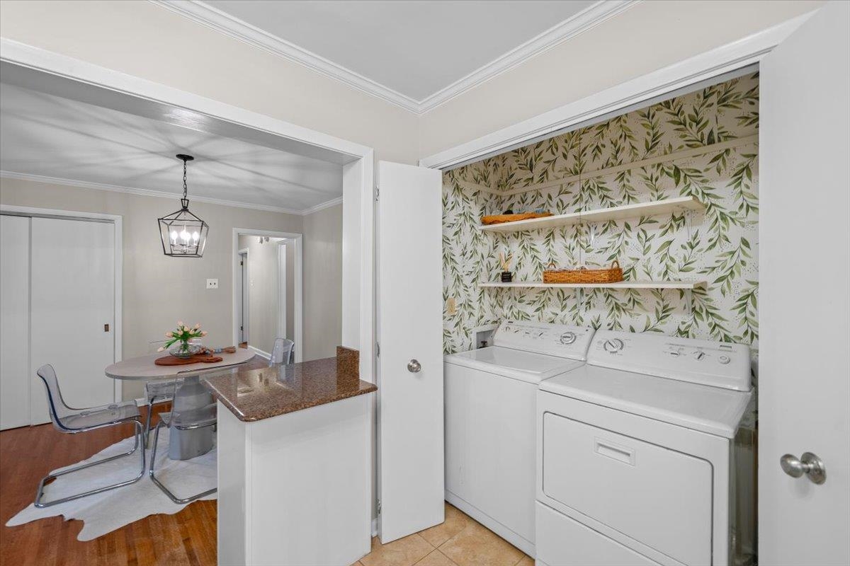 Laundry room with white washer and dryer, leafy wallpaper, and open shelves beside the dining area.