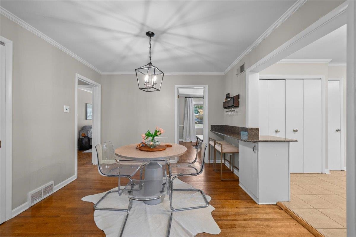 Dining area with a round table, clear chairs, hardwood floors, and a kitchen counter.