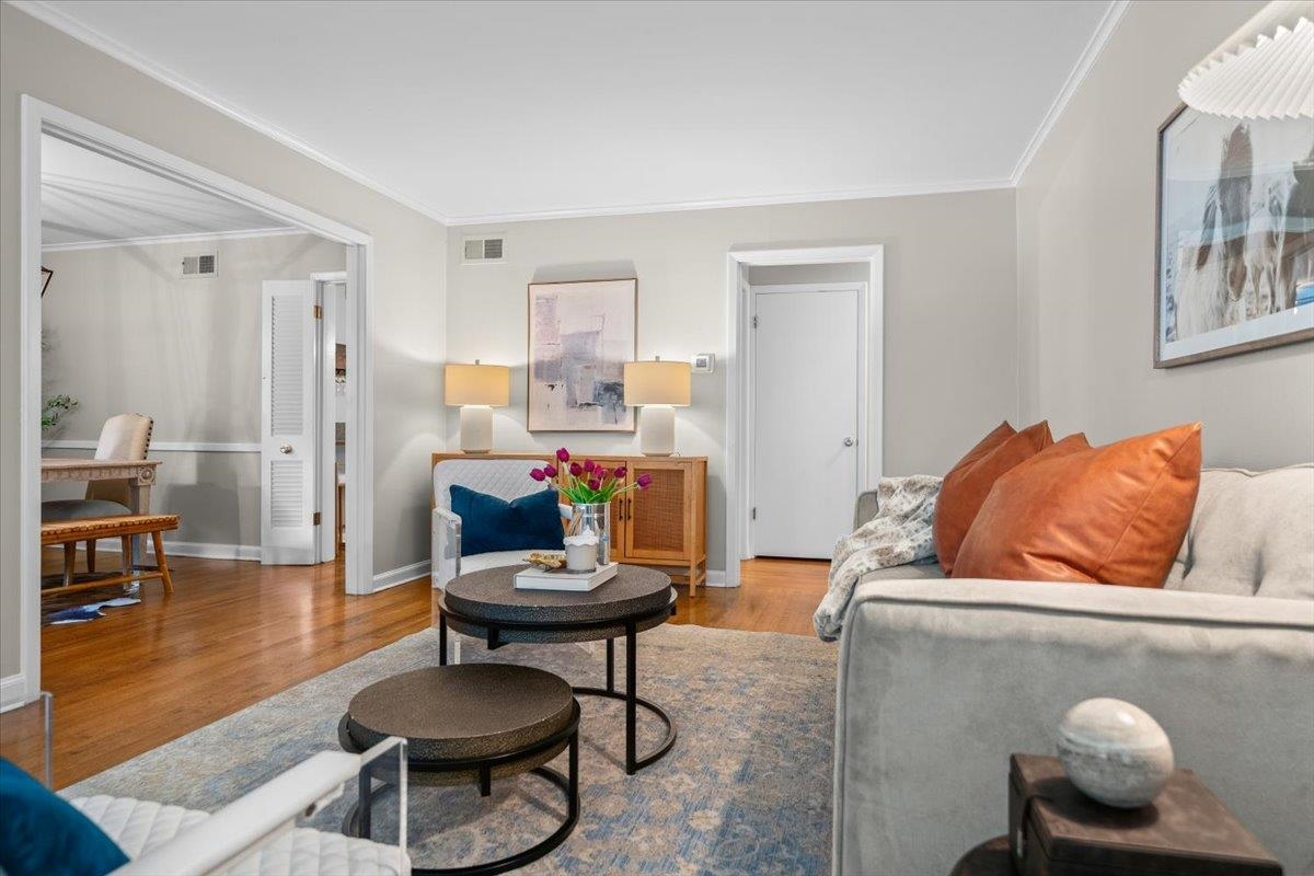 Living room with gray sofa, rust-colored pillows, round coffee tables, and hardwood floors.
