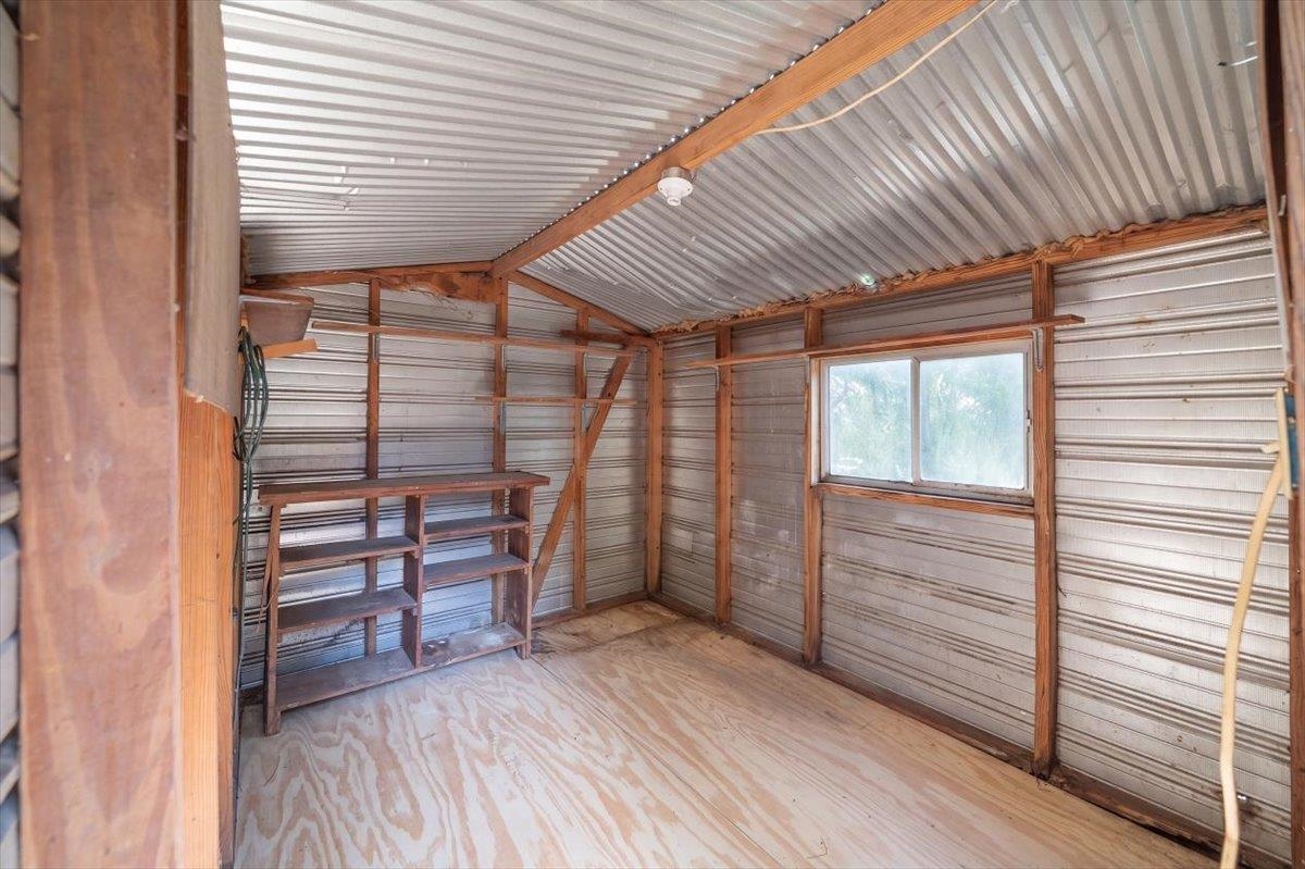 Workshop with corrugated metal walls, exposed wood framing, built-in shelves, and a window.
