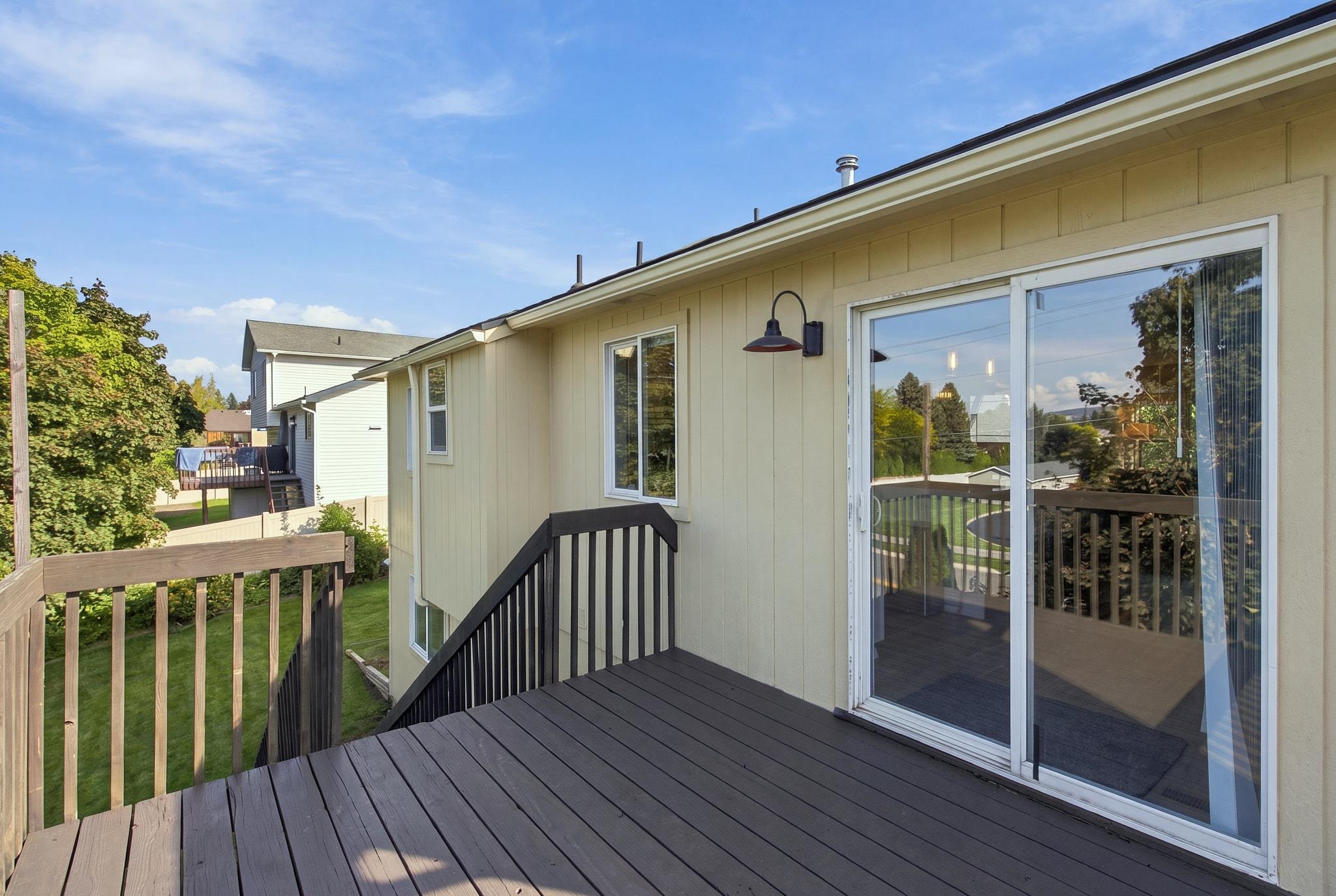 Elevated rear deck with dark flooring, black railings, and a sliding glass door.