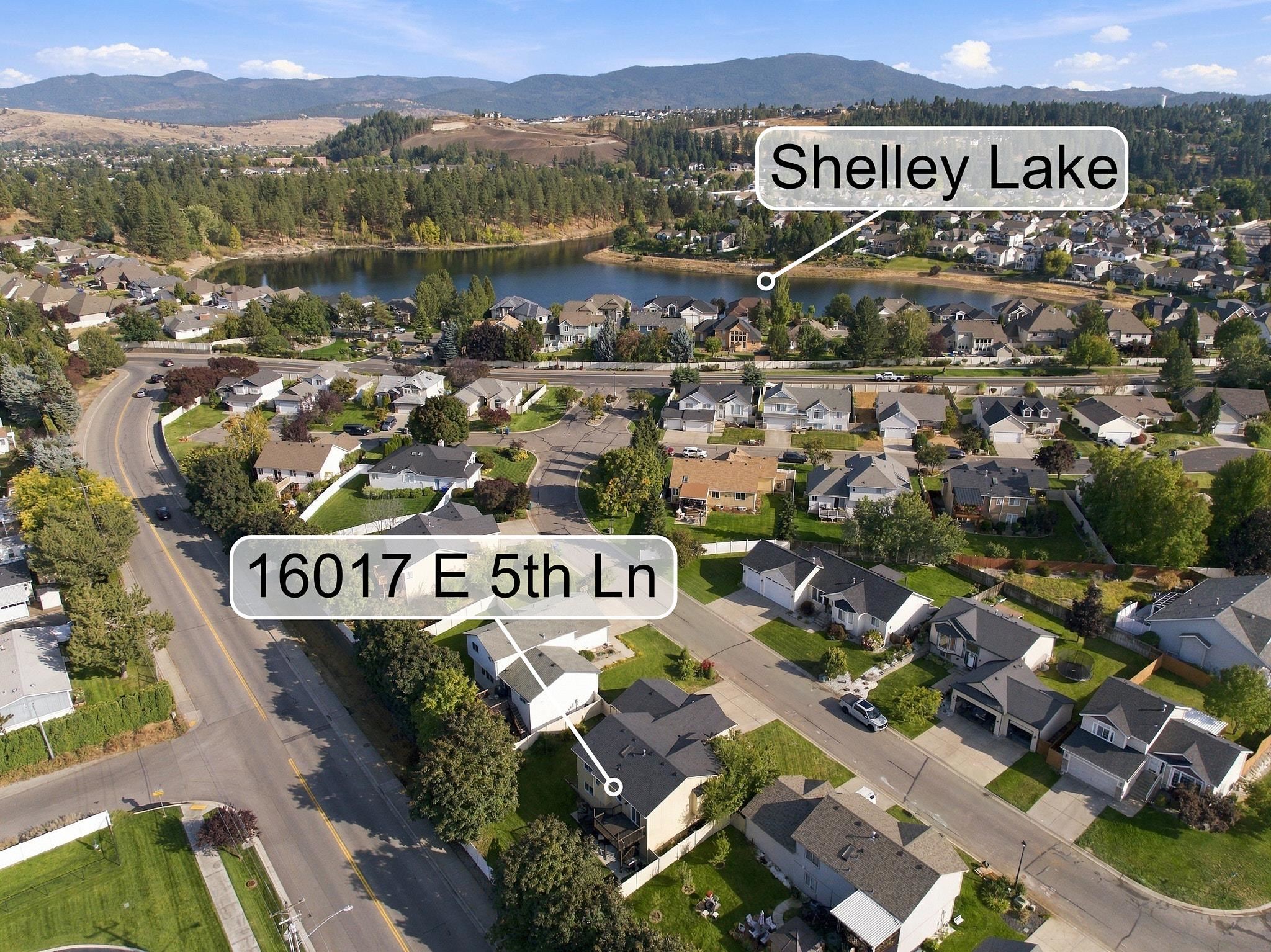 Aerial view of 16017 E 5th Ln near Shelley Lake, with surrounding homes and mountains.
