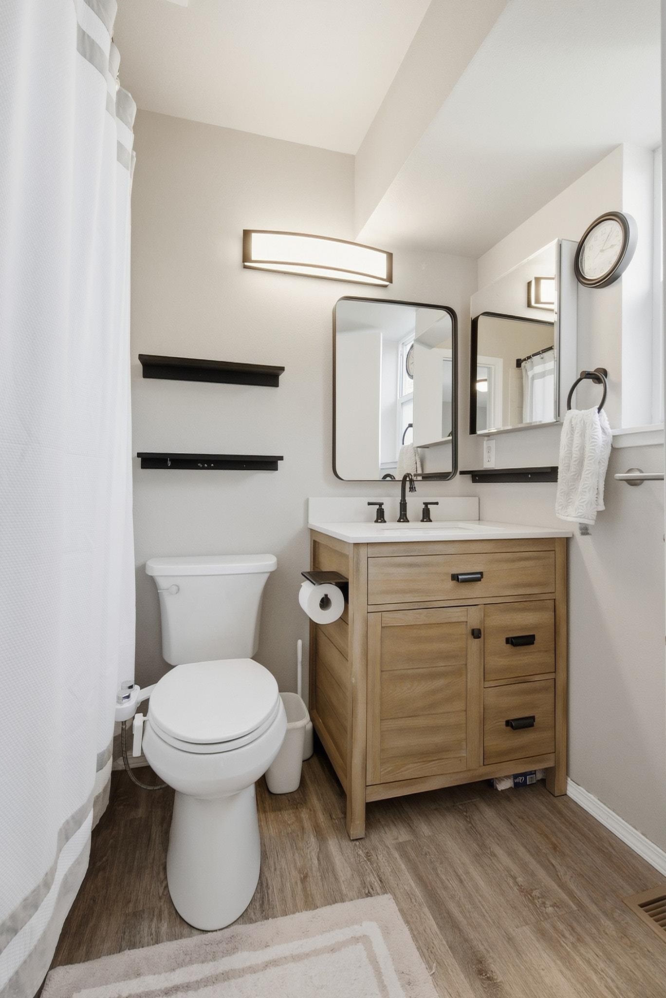 Bathroom with a wood-grain vanity, black-framed mirrors, and white toilet.