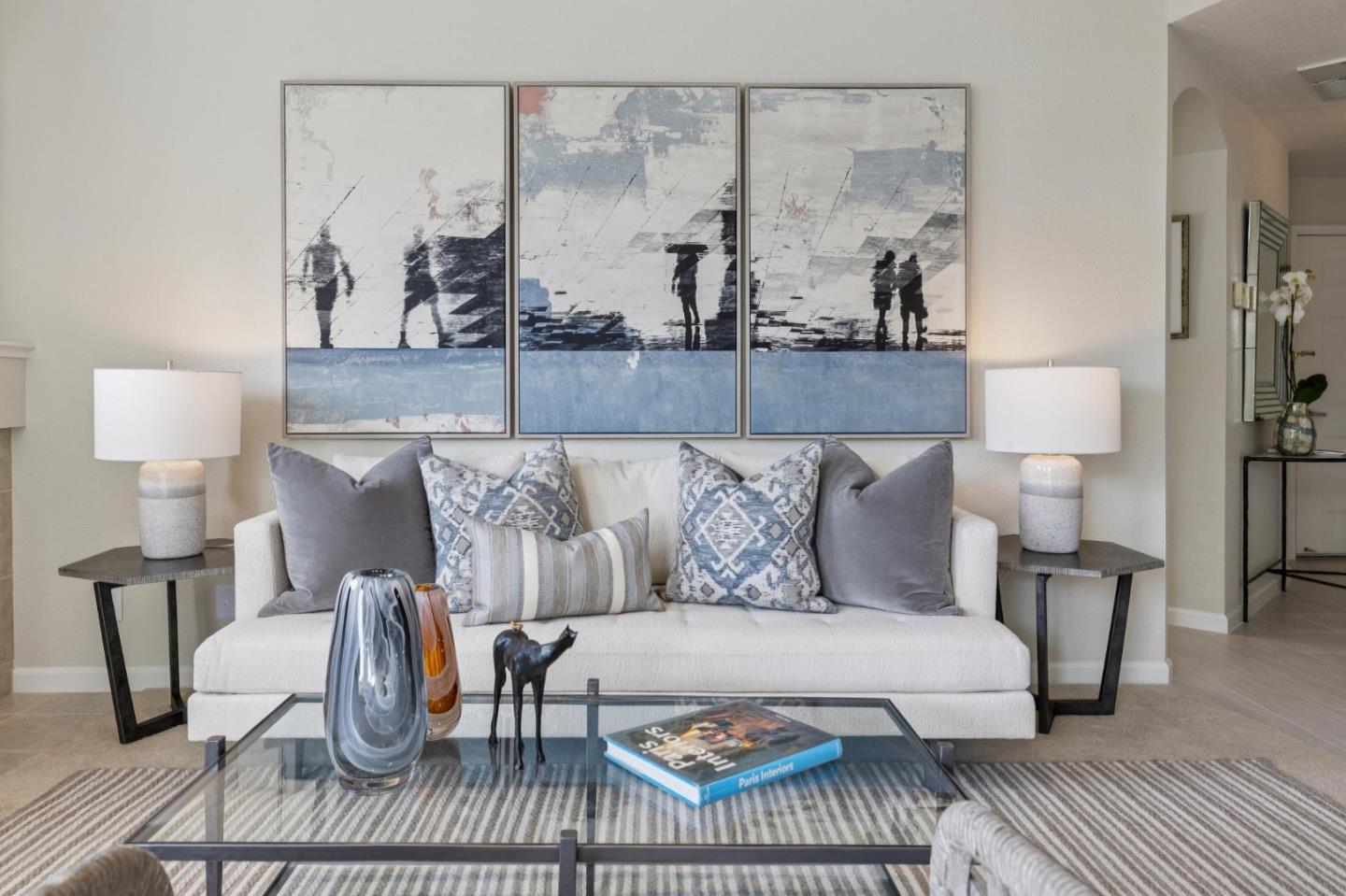 Staged living room with a white sofa, blue-gray cushions, and three large abstract artworks.