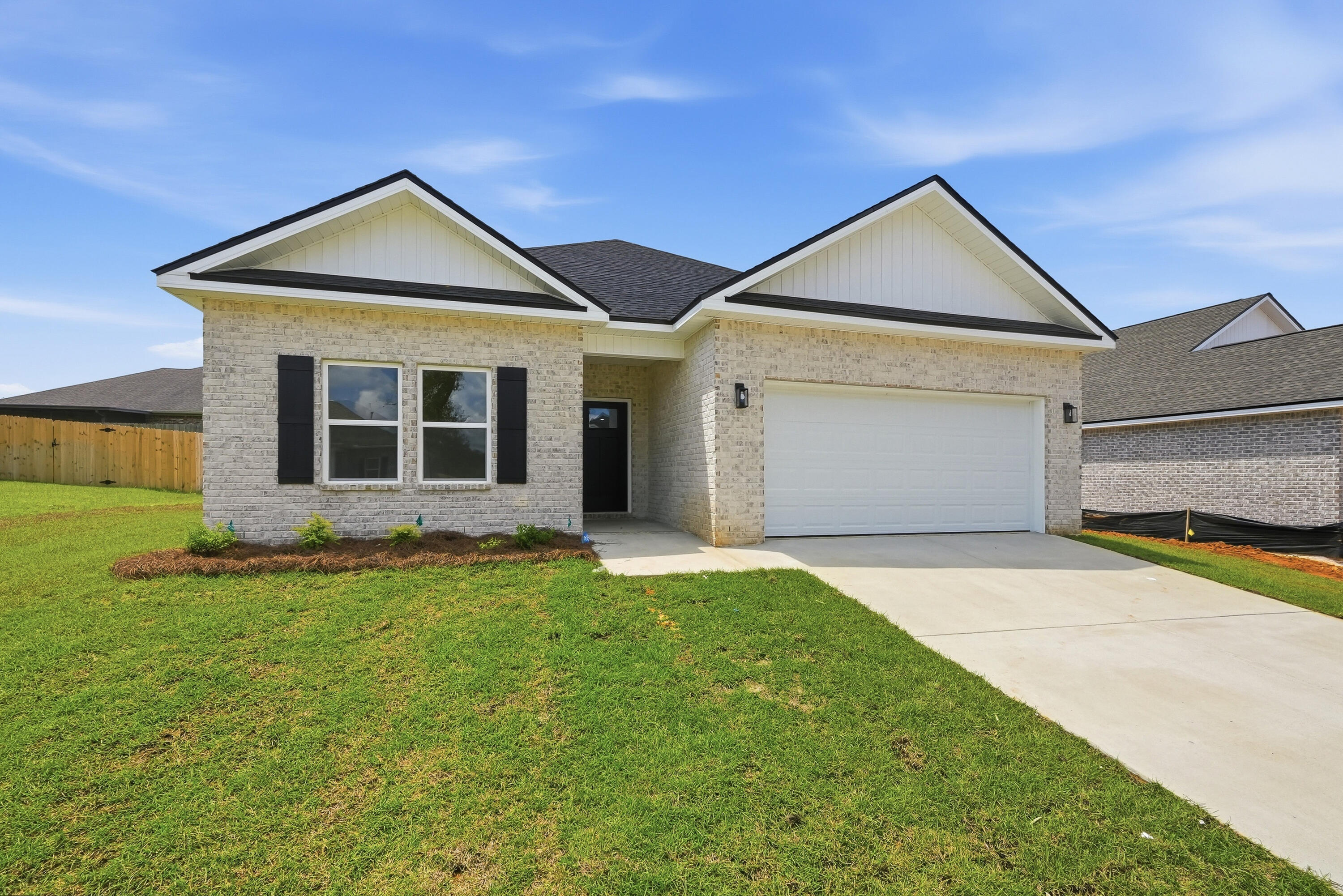 Single-story light brick home with two front gables, black shutters, and a white double garage.