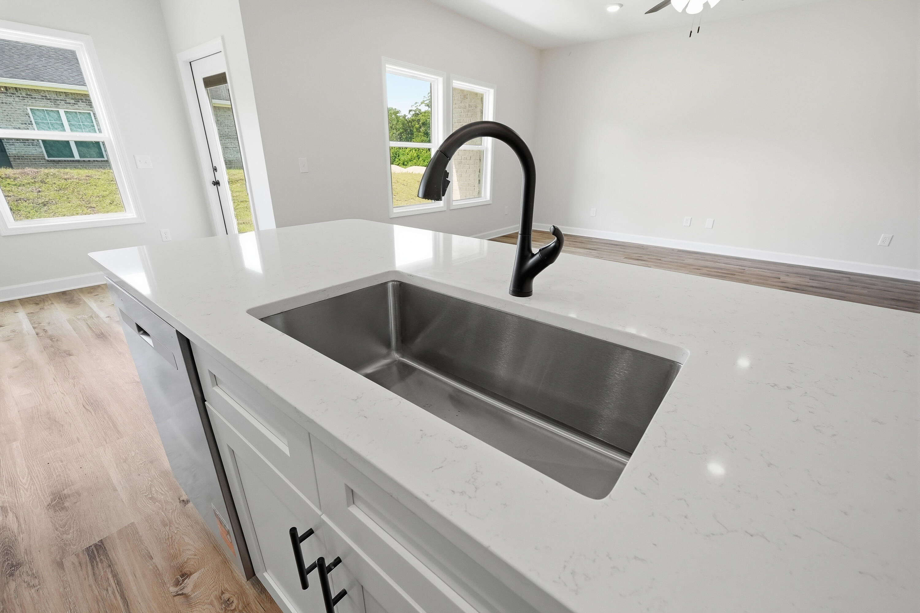 Kitchen island with a deep stainless steel sink, white veined countertop, and black gooseneck faucet.