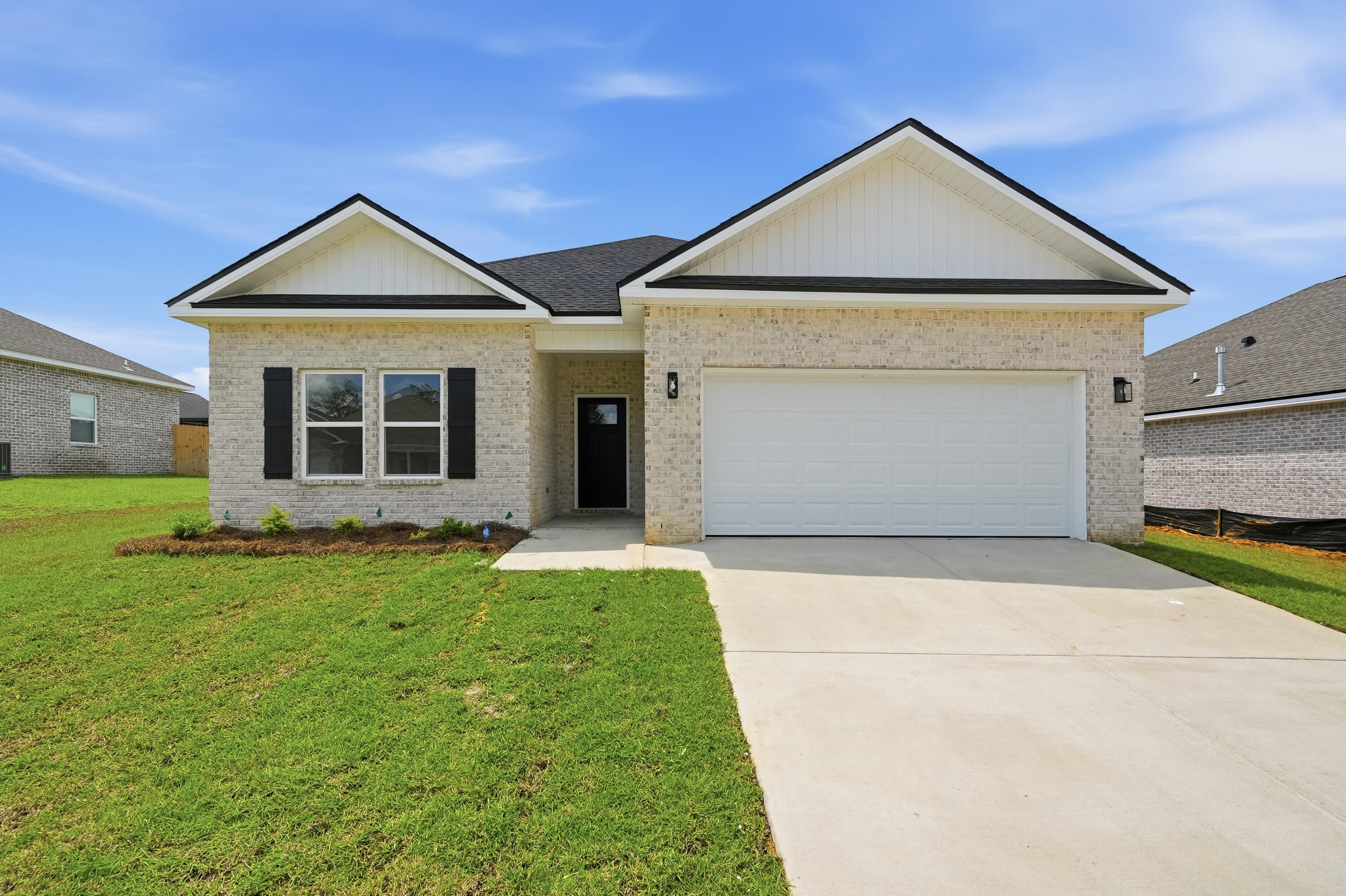 Light brick single-story home with twin gables, black shutters, and a wide two-car garage.