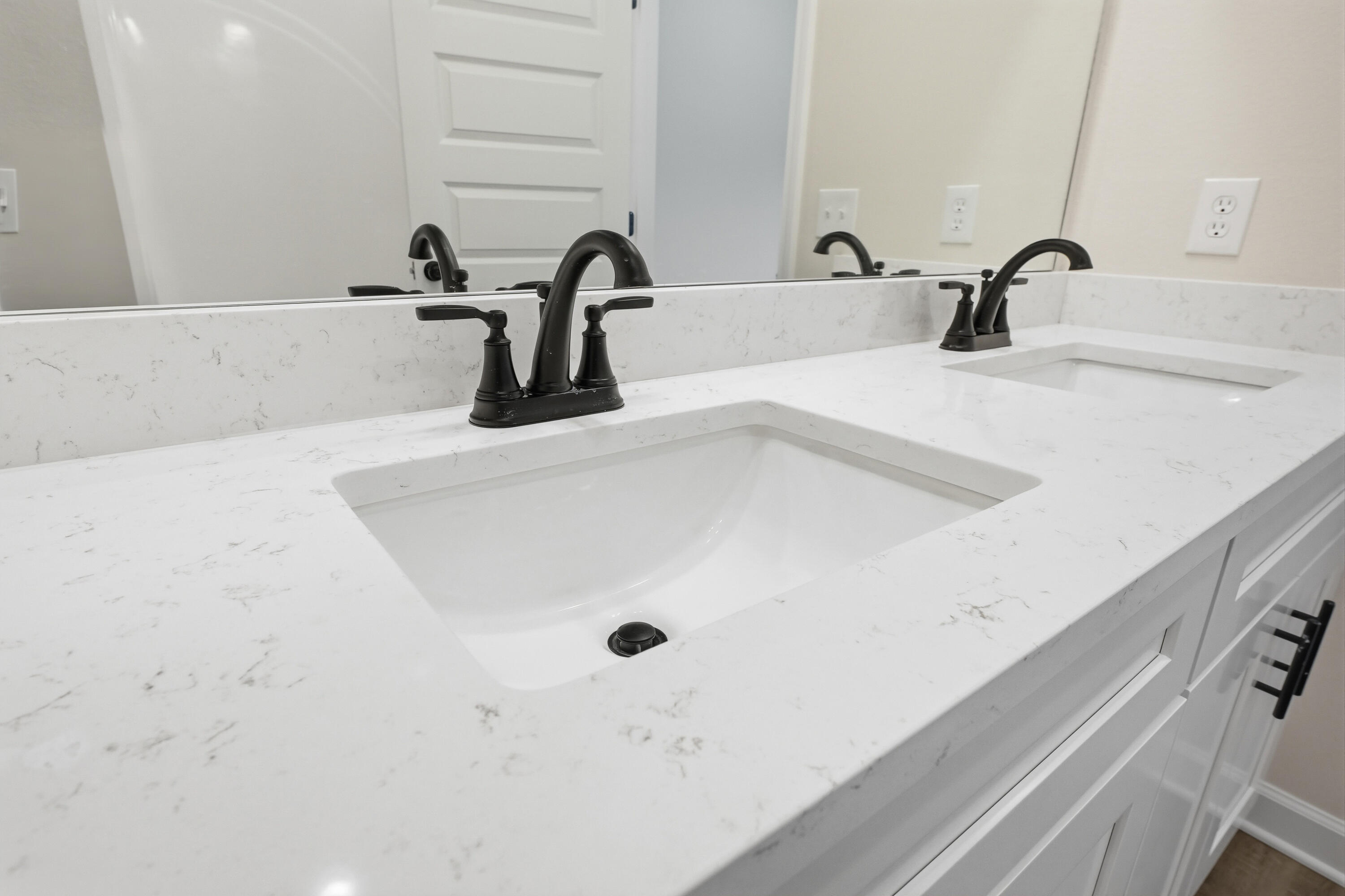 Bathroom vanity with two sinks, a white veined countertop, and matte black faucets.