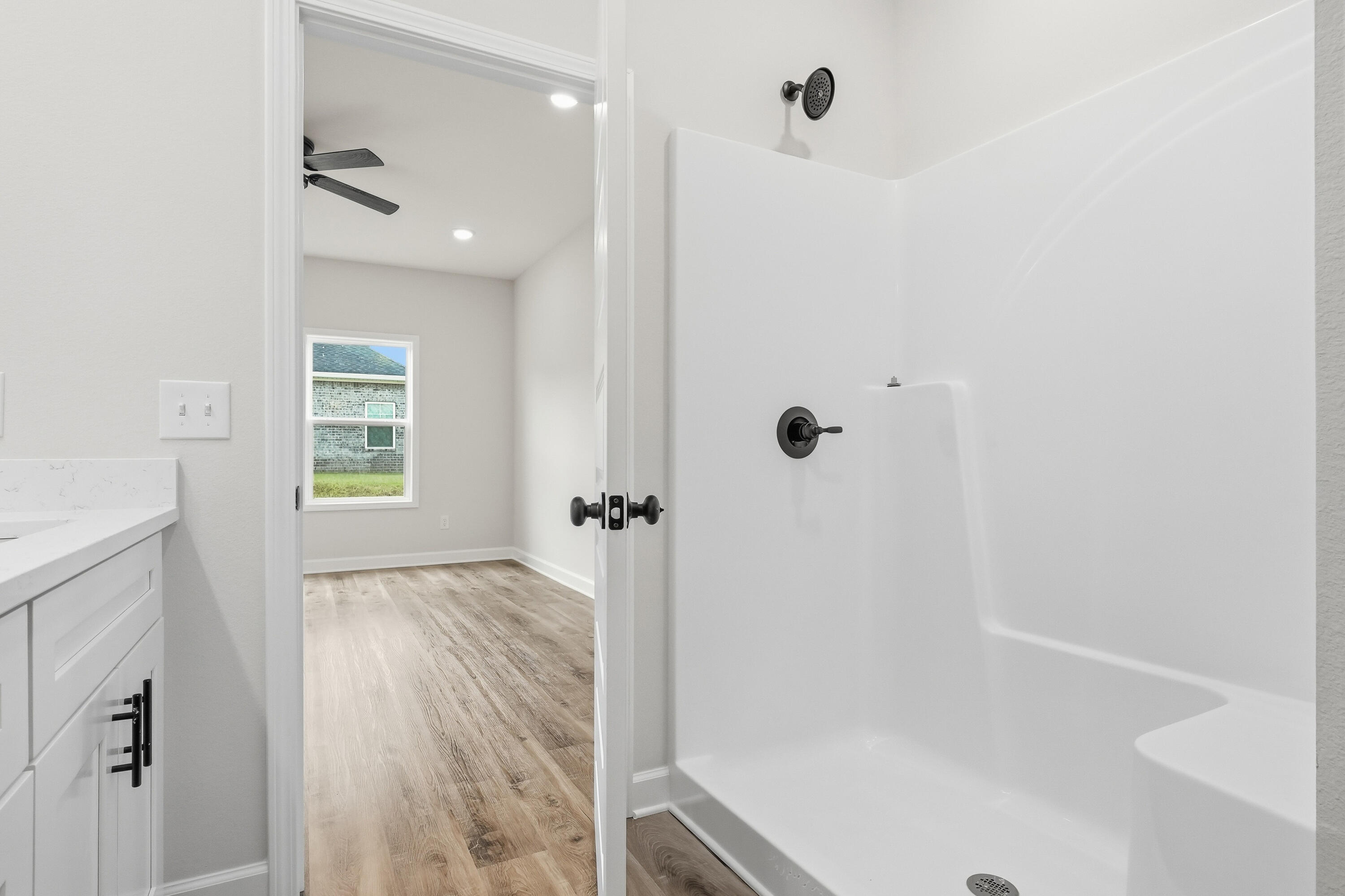 Bathroom with a white tub, black fixtures, and an open doorway to an empty room.