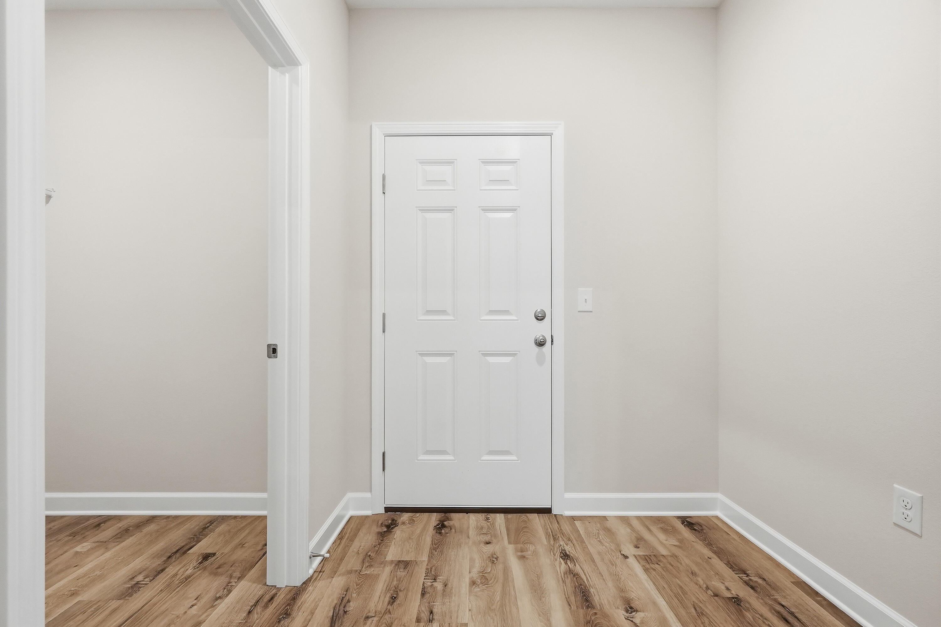 Unfurnished entryway with a white paneled front door and wood-look plank flooring.