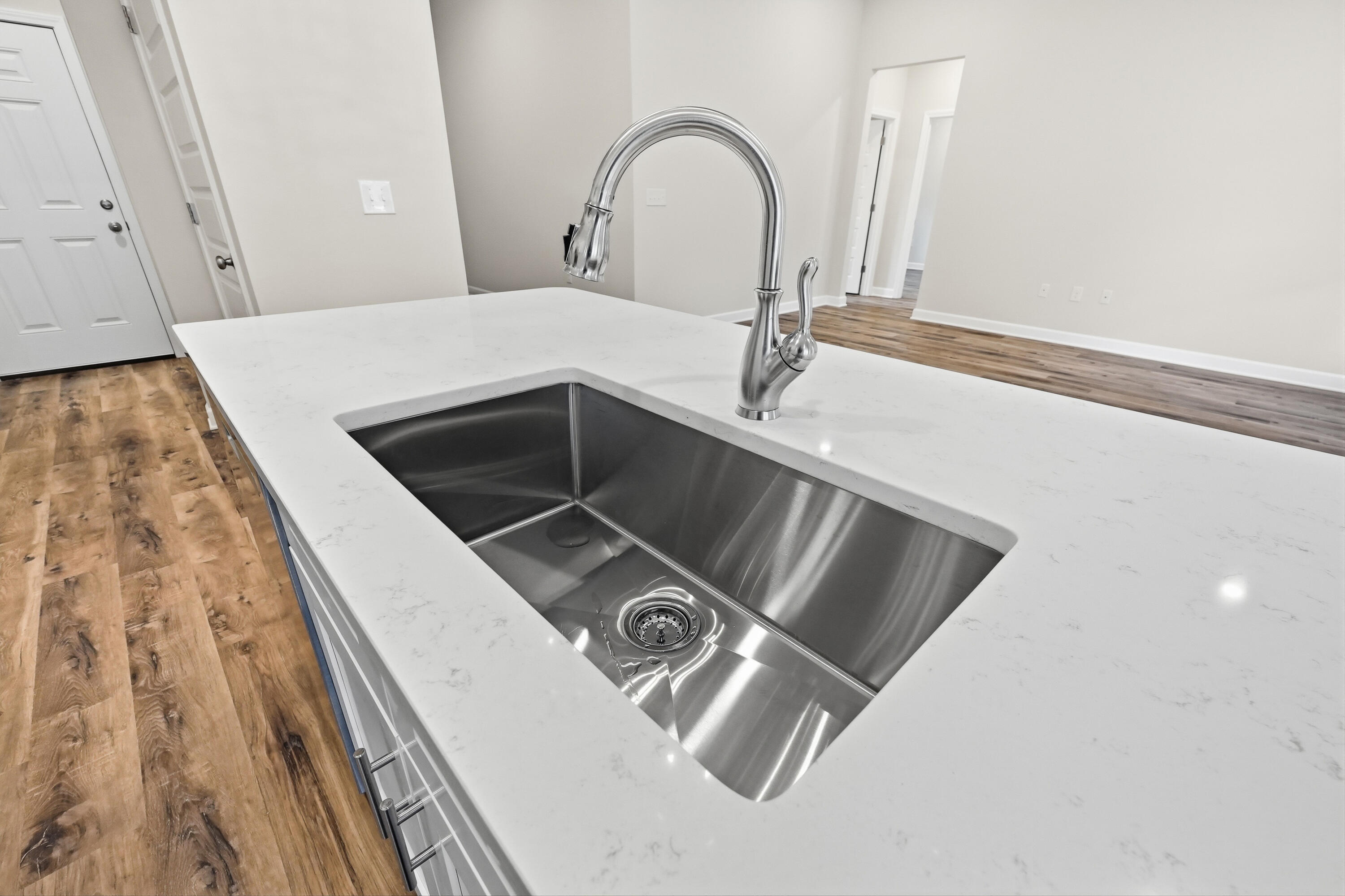 Kitchen island with a large stainless-steel sink, chrome faucet, and white veined countertop.