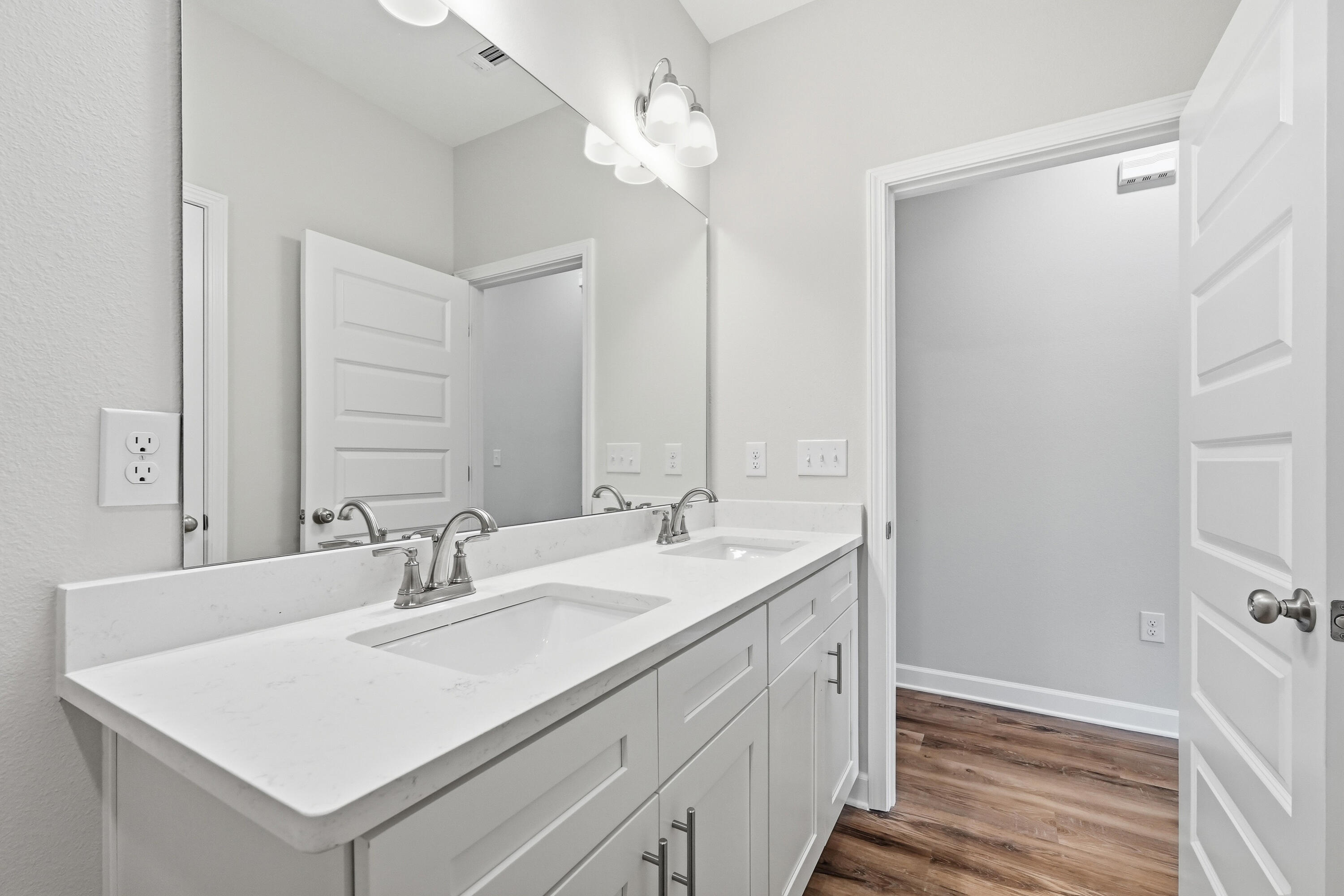 Bathroom with a long double-sink vanity, white cabinetry, and a large mirror.