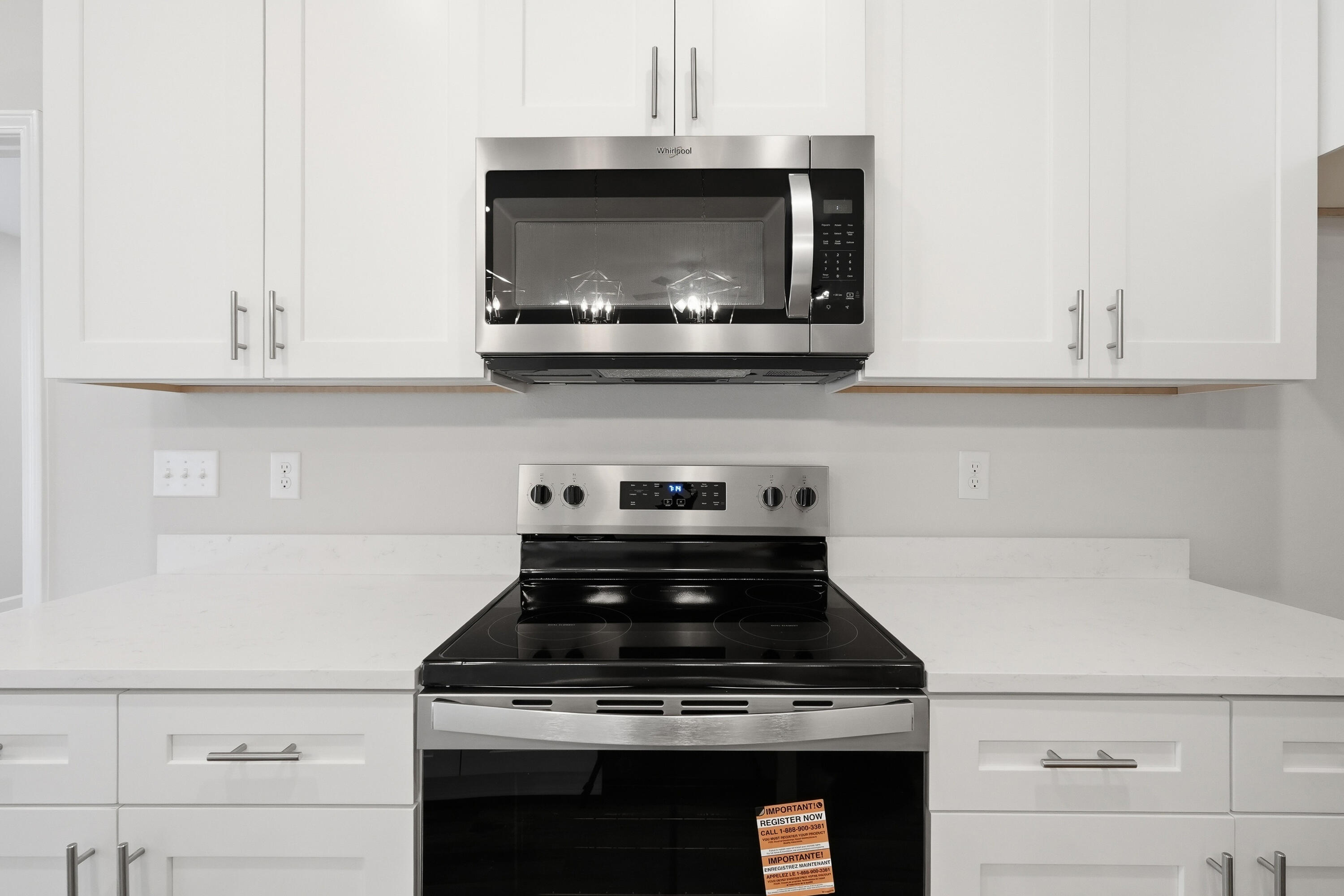 Kitchen with white shaker cabinets, white counters, and a stainless-steel range and microwave.