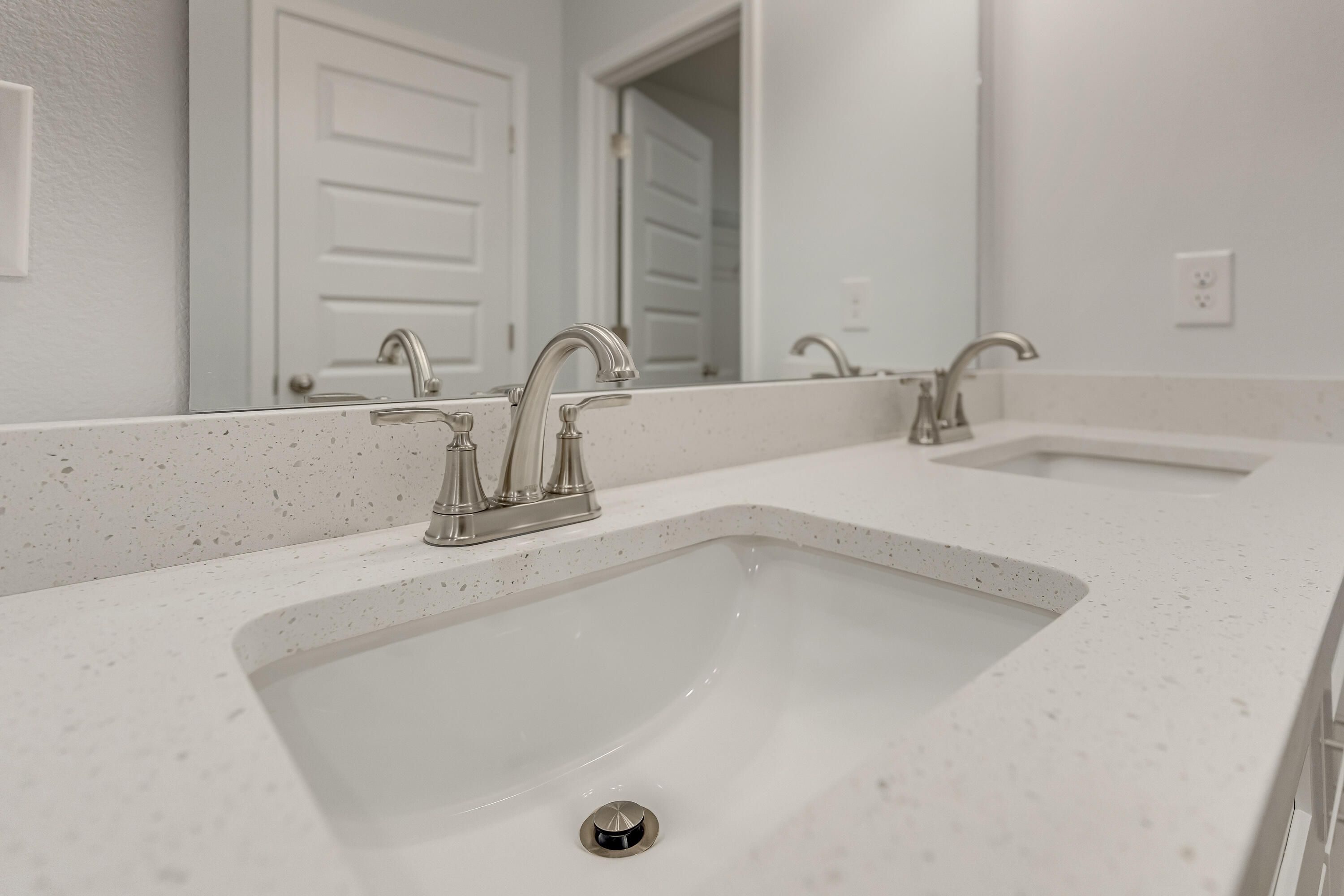Bathroom vanity with a speckled countertop, undermount sink, and brushed-nickel faucet.