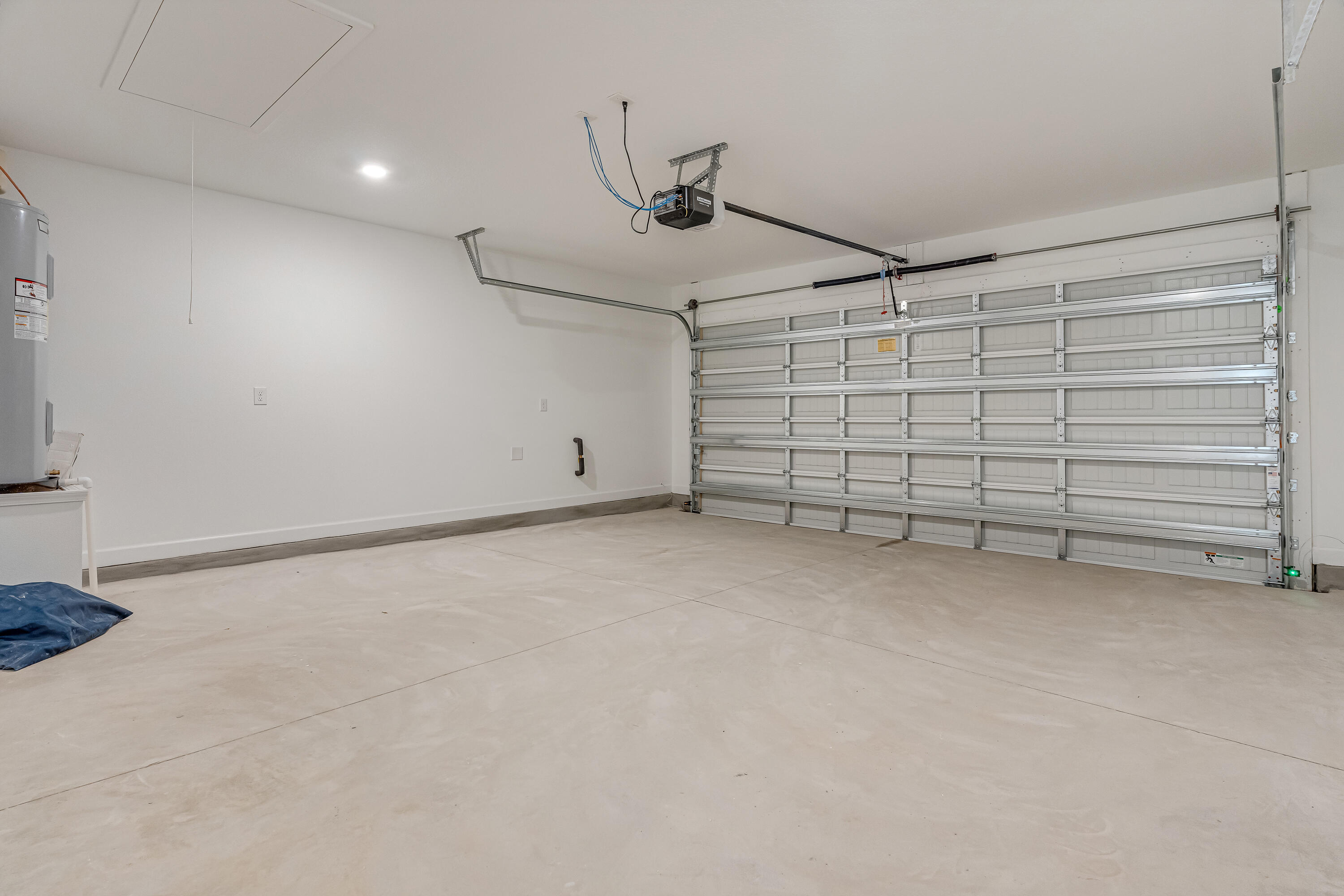 Empty garage with a large segmented door, ceiling opener, and concrete floor.