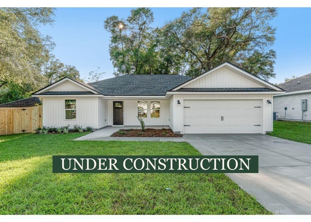 Single-story white house with a two-car garage, lawn, and an “UNDER CONSTRUCTION” banner.
